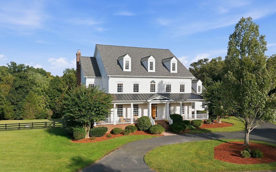 Professional listing photo of a white colonial home under a blue sky