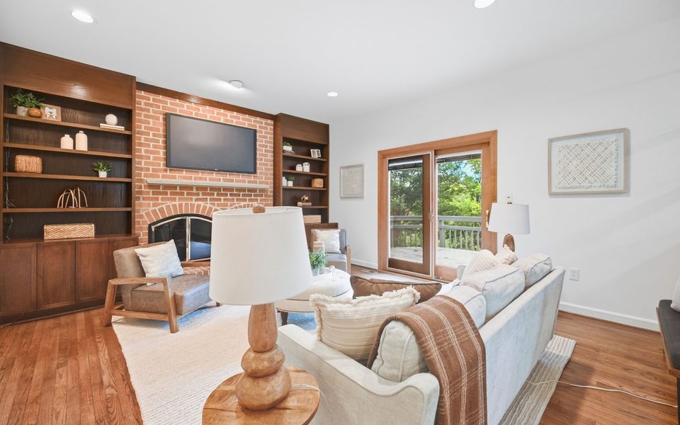 A professionally staged family room with a brick fireplace and built-in shelves